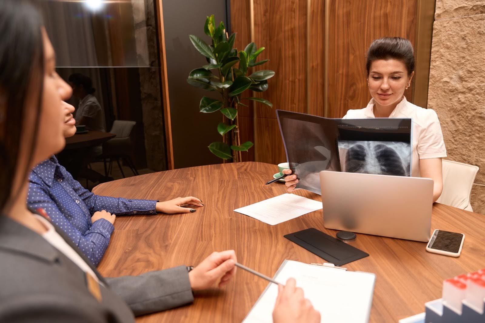 A lawyer looking at X-rays during a deposition while the plaintiff looks on with confidence because her attorney learned how to prepare for a deposition in Georgia.